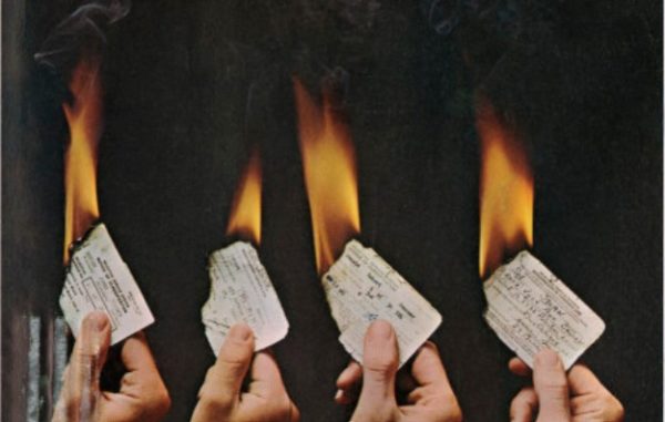 4 draft card that are on fire being held by 4 right hands. From the cover of Ramparts magazine
