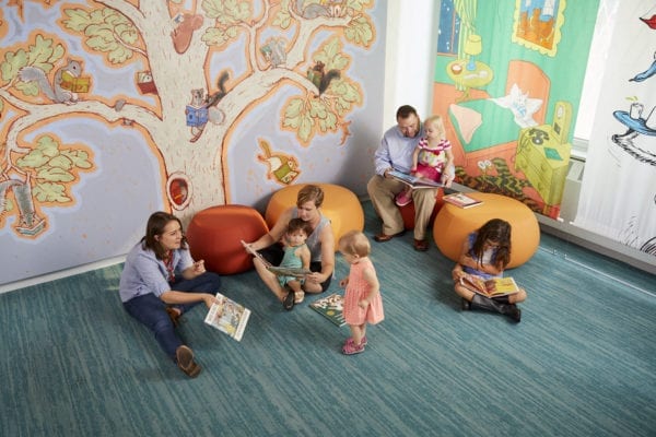 Three adults and four children of various ages read and talk together on stools and the floor of the children's literature gallery at the American Writers Museum in Chicago