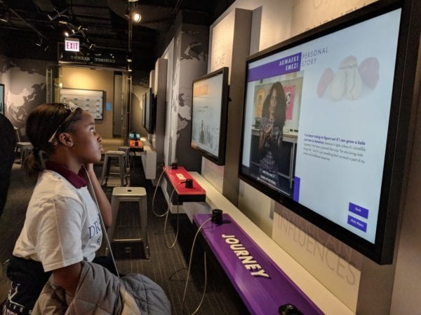 A student listening to the "Journey" kiosk of the My America: Immigrant and Refugee Writers Today exhibit at the American Writers Museum