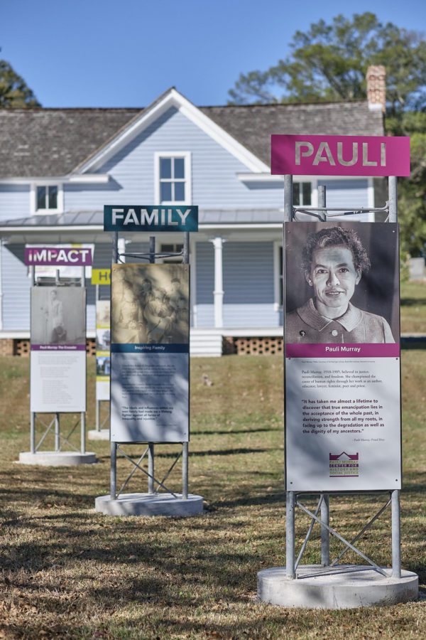 An exhibit outside of the Pauli Murray Center for History and Social Justice with signs that say Pauli, Family, and Act visible with Murray's childhood home in the background.